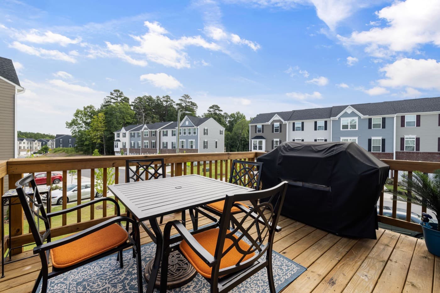 Finished wood deck with black railing and outdoor dining set off a two-story home
