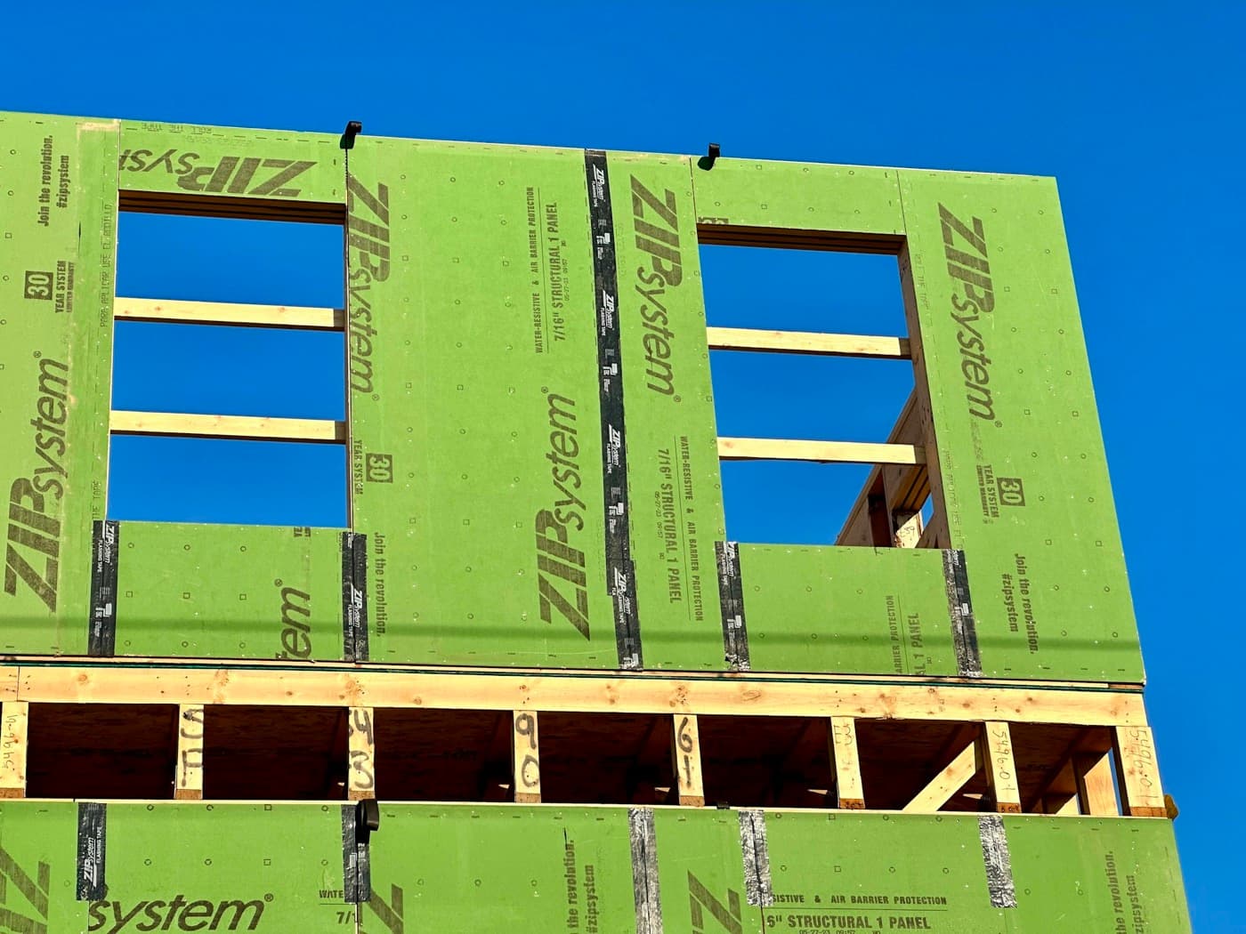 New home exterior wrapped in weather-resistant sheathing during construction, window openings framed