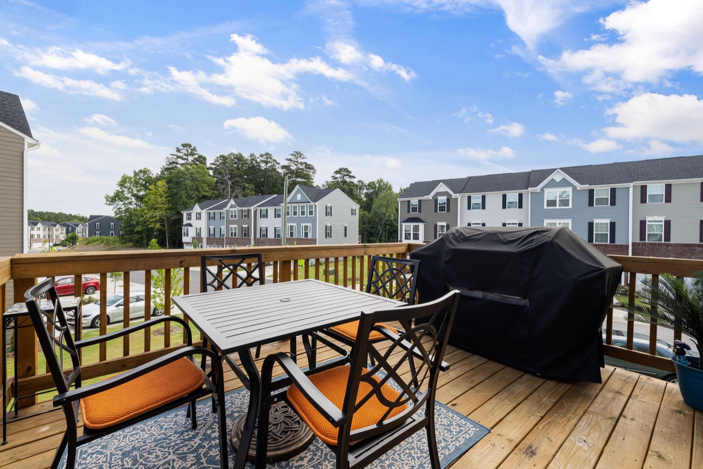 Finished wood deck with black railing and outdoor dining set off a two-story home