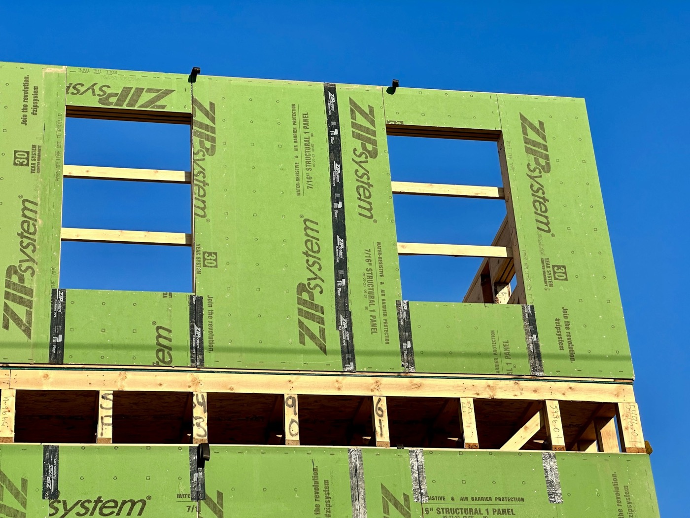 New home exterior wrapped in weather-resistant sheathing during construction, window openings framed
