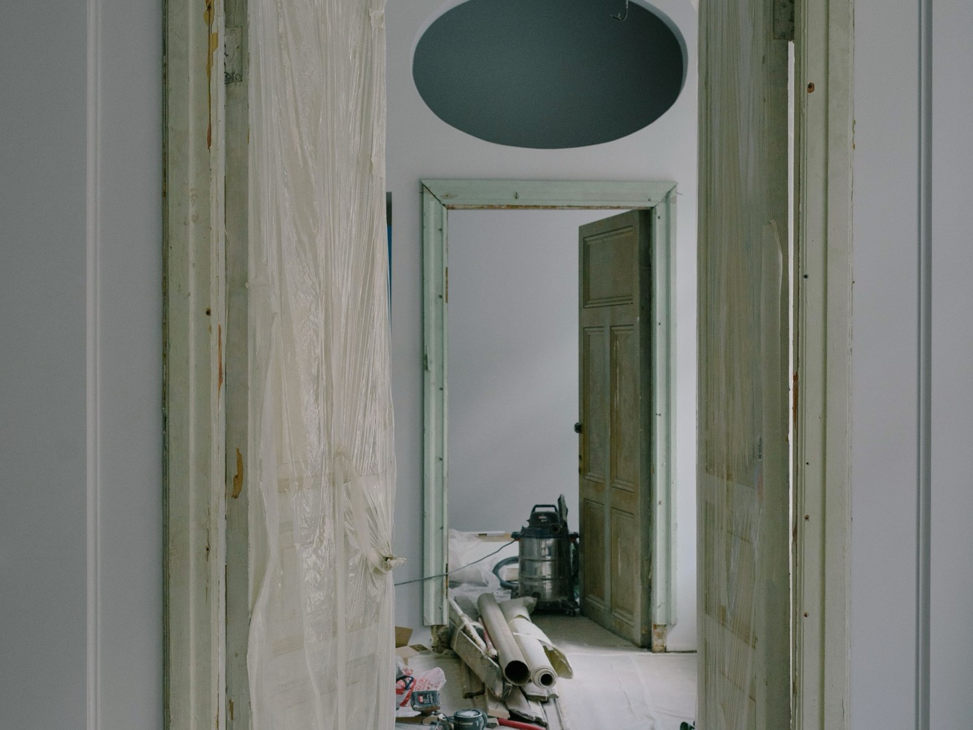 Home hallway mid-remodel with plastic sheeting over doorways and tools staged on the floor